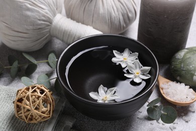 Beautiful composition with herbal massage bags, spa products and flowers on light grey table