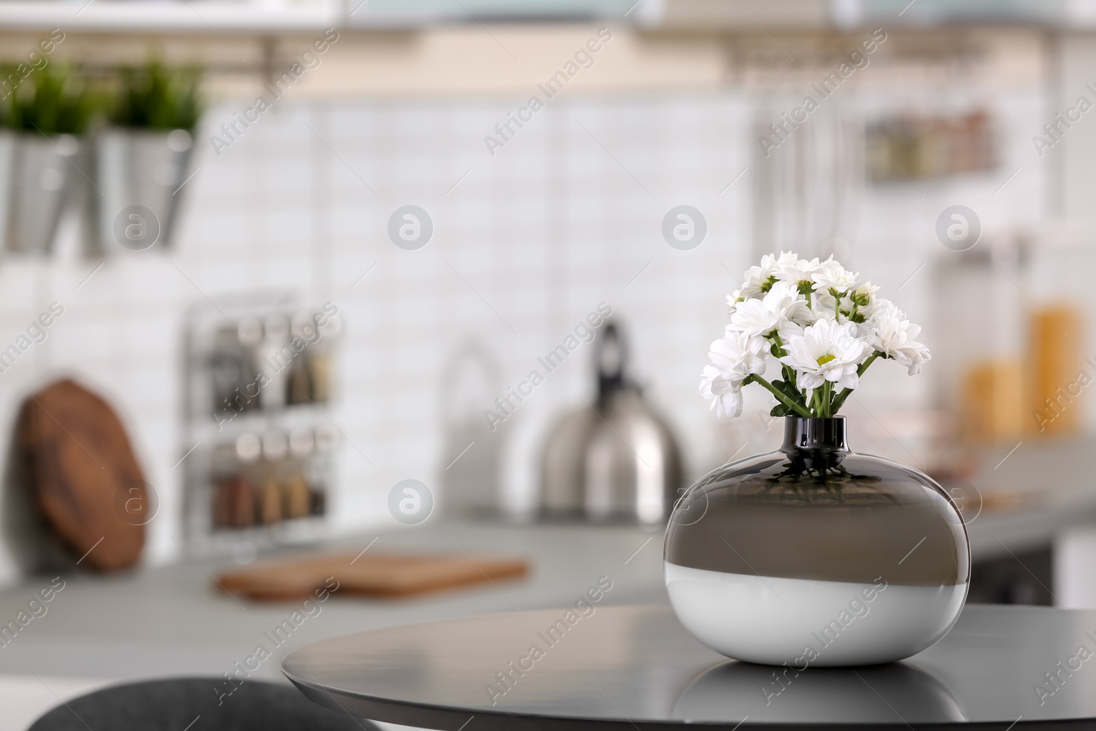 Photo of Vase with beautiful flowers on table in kitchen interior. Space for text