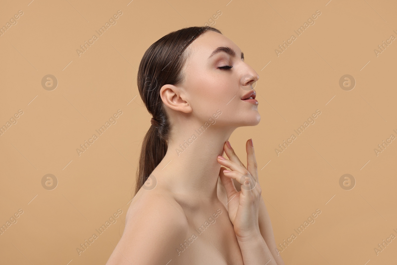 Photo of Beautiful woman touching her neck on beige background