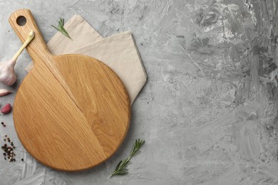 Photo of Cutting board, garlic, spices and rosemary on grey textured table, flat lay. Space for text