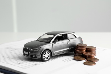 Toy car, money and insurance contract on table