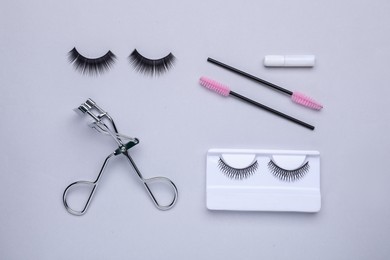 Photo of Flat lay composition with fake eyelashes, brushes and tool on light grey background