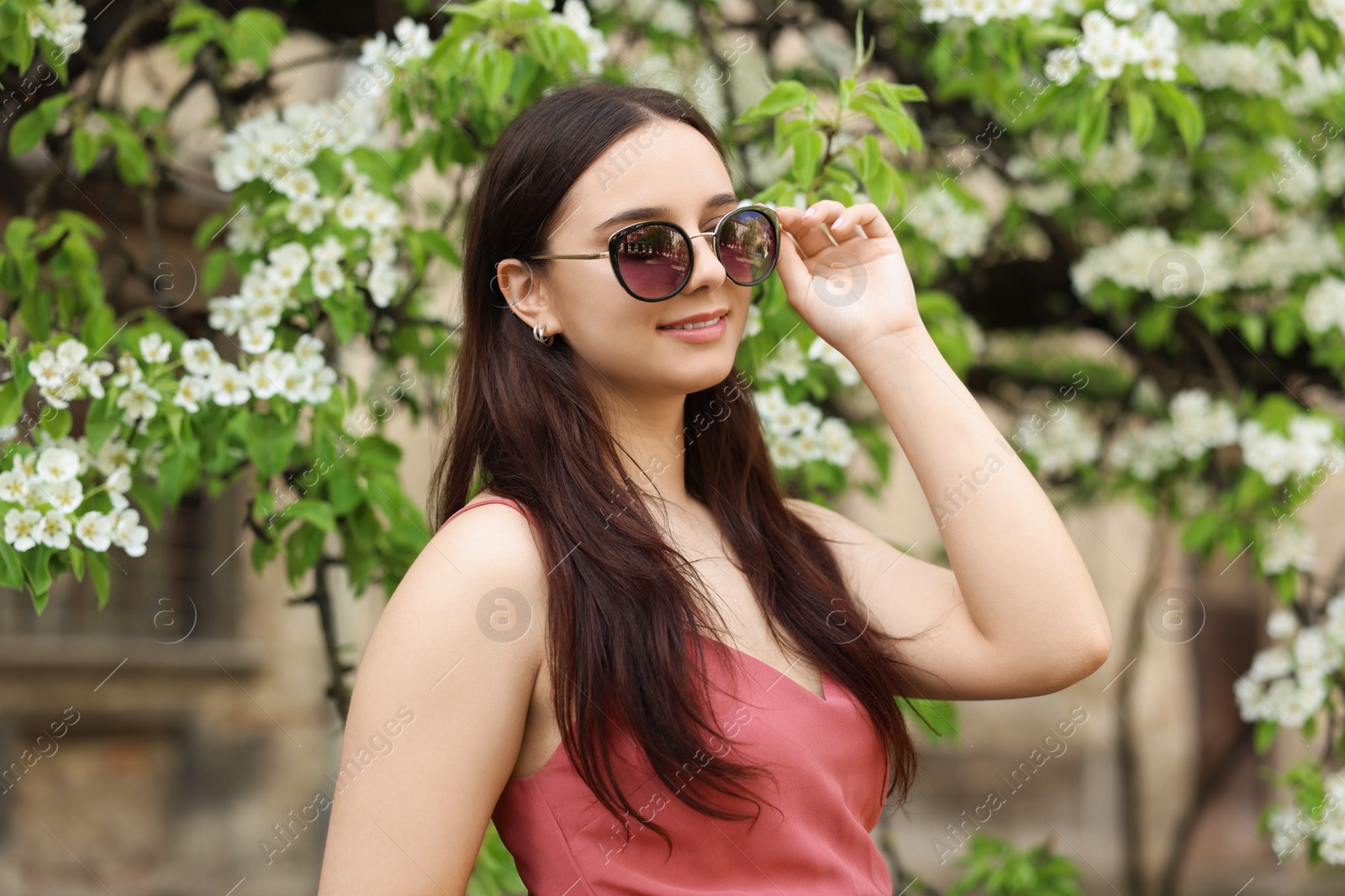 Photo of Beautiful woman in sunglasses near blossoming tree on spring day