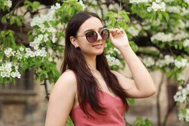 Beautiful woman in sunglasses near blossoming tree on spring day