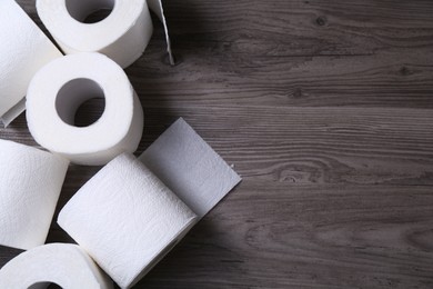 Photo of Soft toilet paper rolls on wooden table, flat lay. Space for text