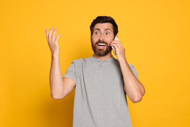 Photo of Emotional man talking on phone against yellow background
