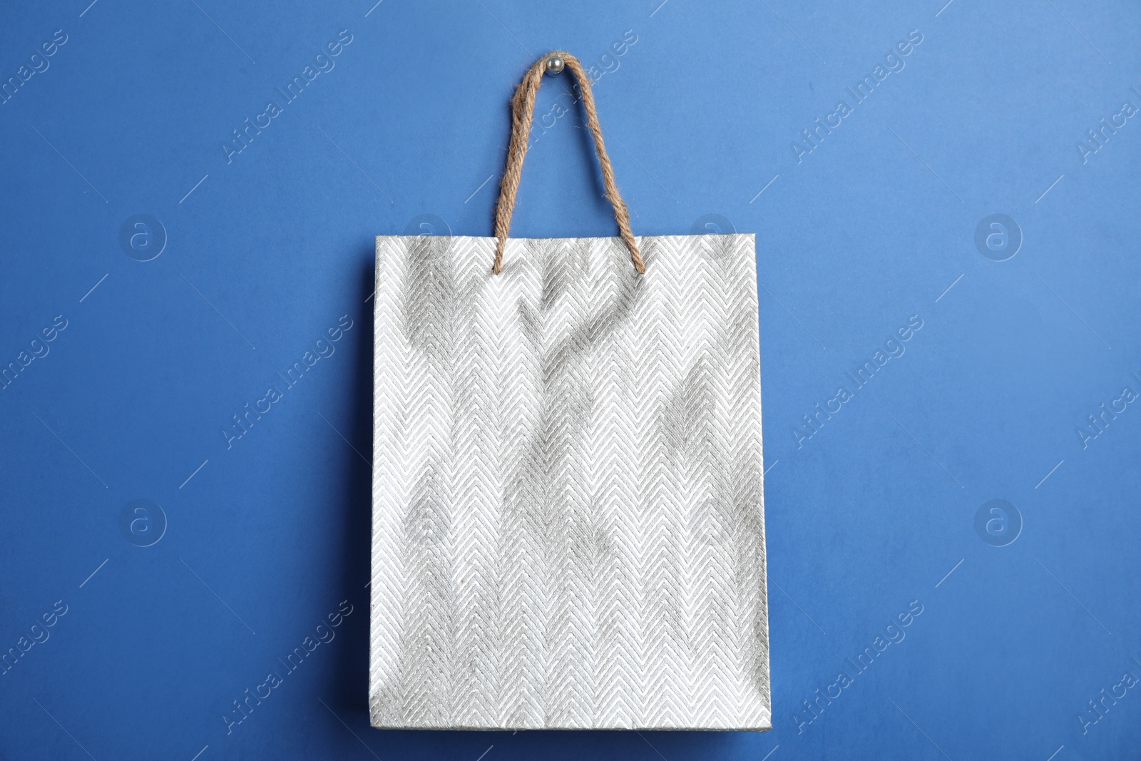 Photo of Silver shopping paper bag on blue background