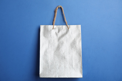 Photo of Silver shopping paper bag on blue background