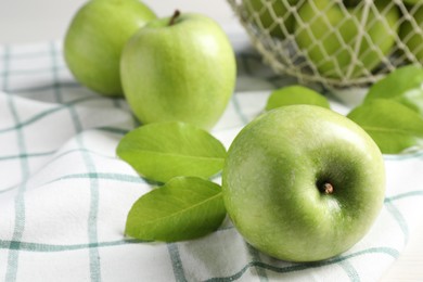 Photo of Fresh ripe green apples with leaves and napkin on table, closeup