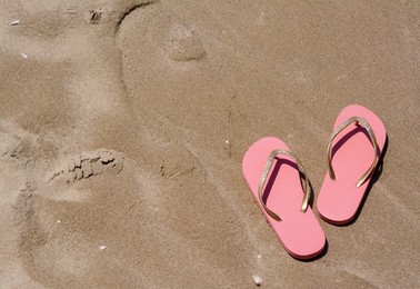 Photo of Stylish pink flip flops on wet sand, above view. Space for text