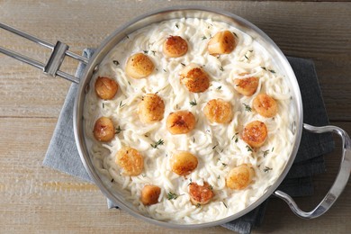 Delicious scallop pasta in pan on wooden table, top view