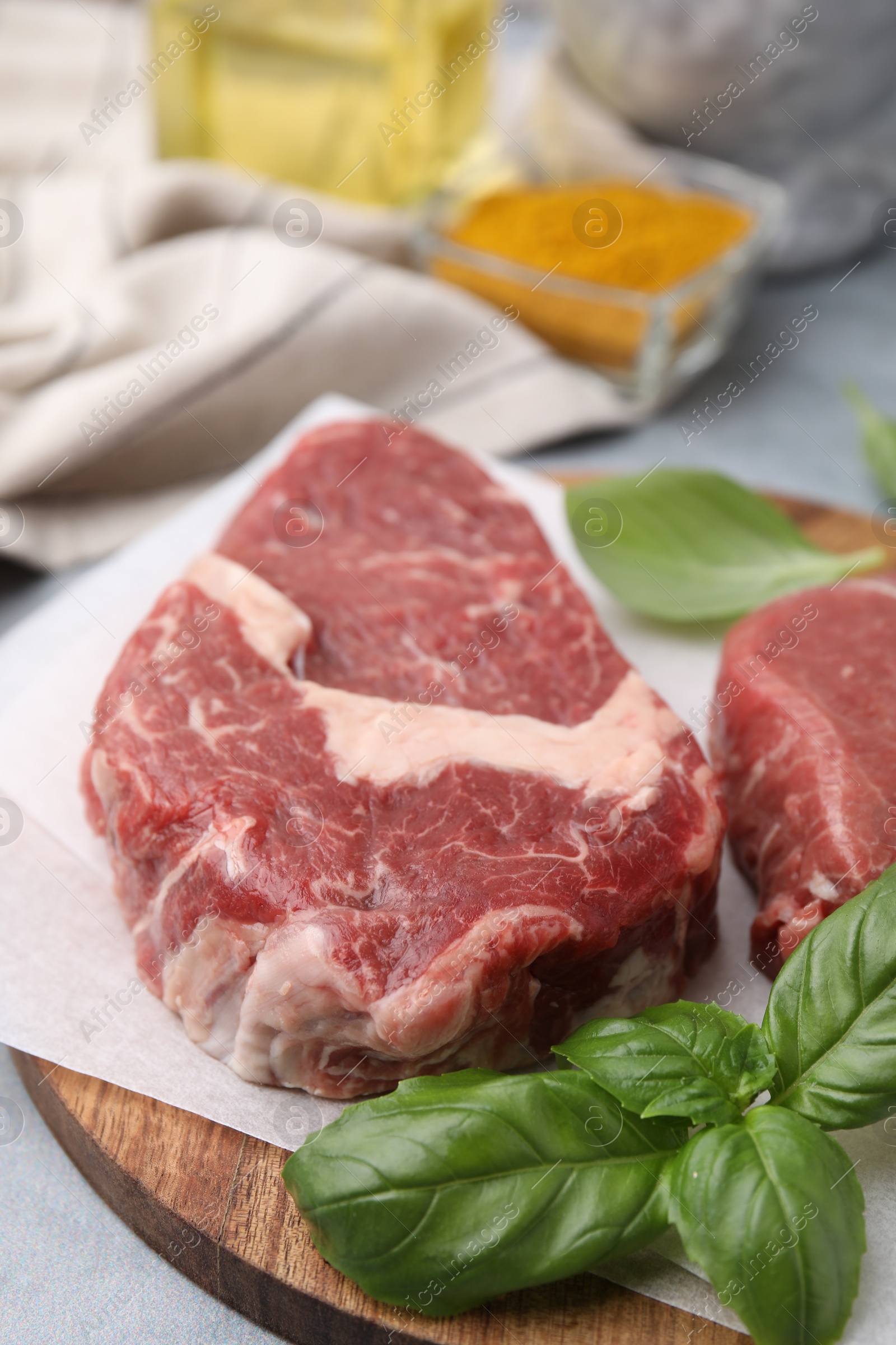 Photo of Cut fresh beef meat with basil leaves on wooden board, closeup