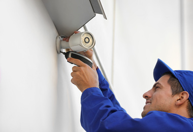 Technician installing CCTV camera on wall outdoors