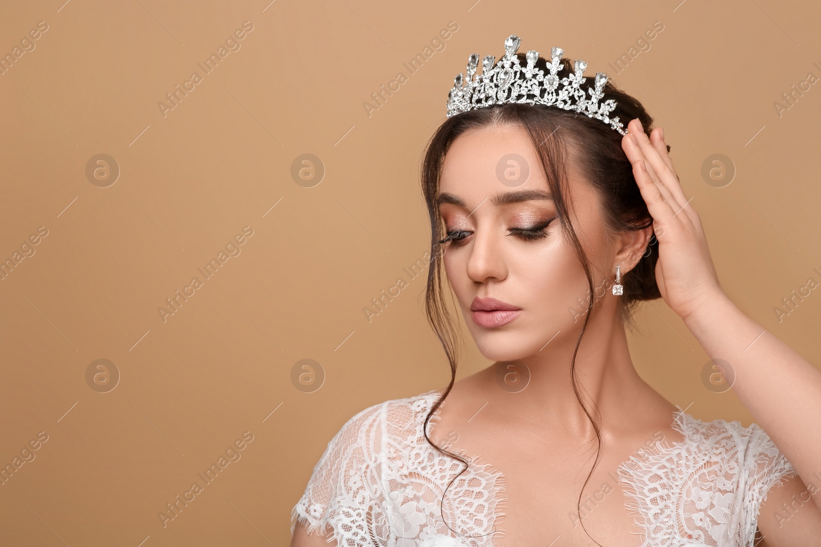 Photo of Beautiful young woman wearing luxurious tiara on beige background, space for text