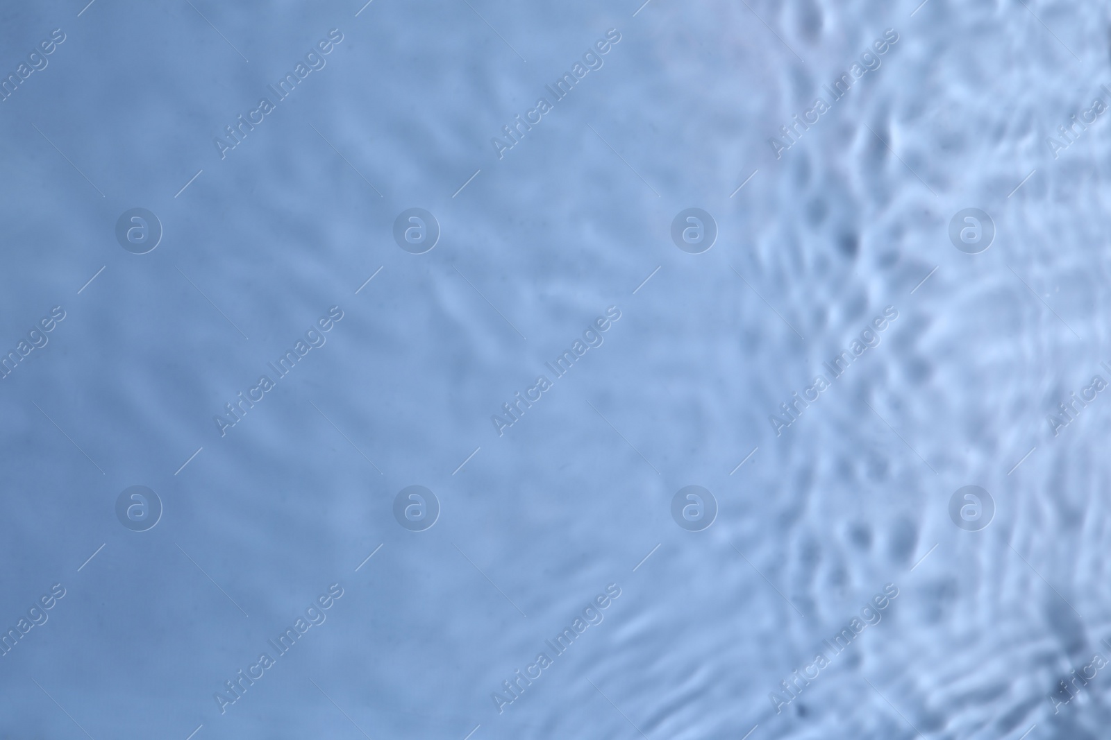 Photo of Closeup view of water with rippled surface on blue background. Space for text