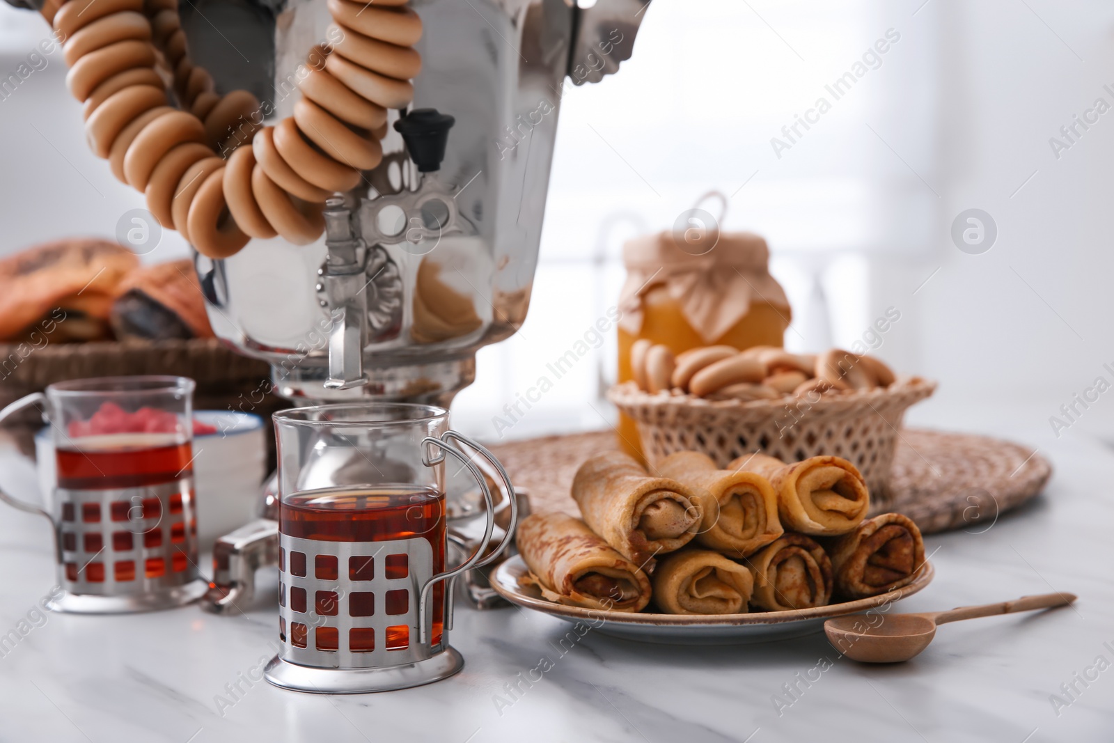 Photo of Traditional Russian samovar with treats on white table at home