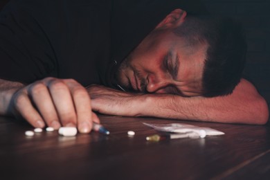 Photo of Overdosed man near different drugs at table