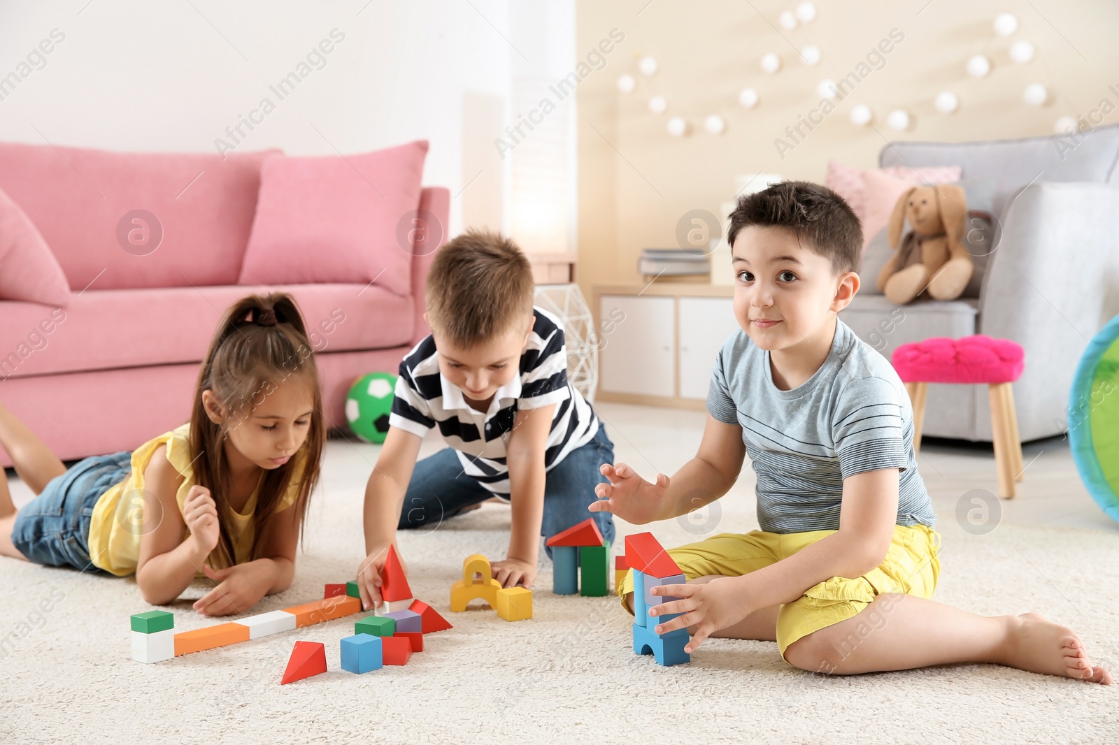 Photo of Cute little children playing with building blocks on floor, indoors
