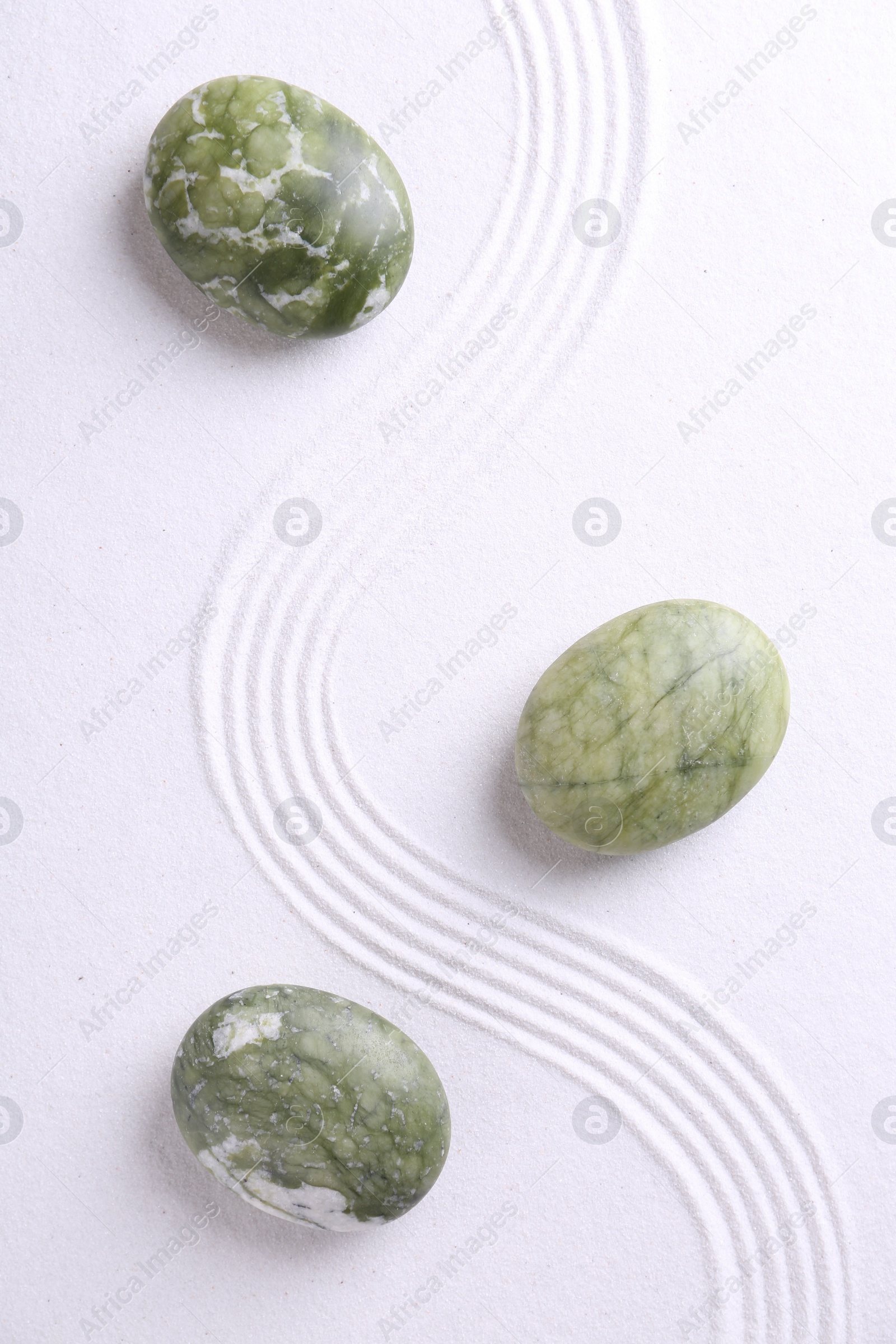 Photo of Zen concept. Stones and pattern on white sand, flat lay