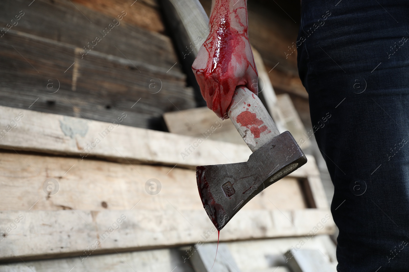 Photo of Man holding bloody axe outdoors, closeup. Space for text