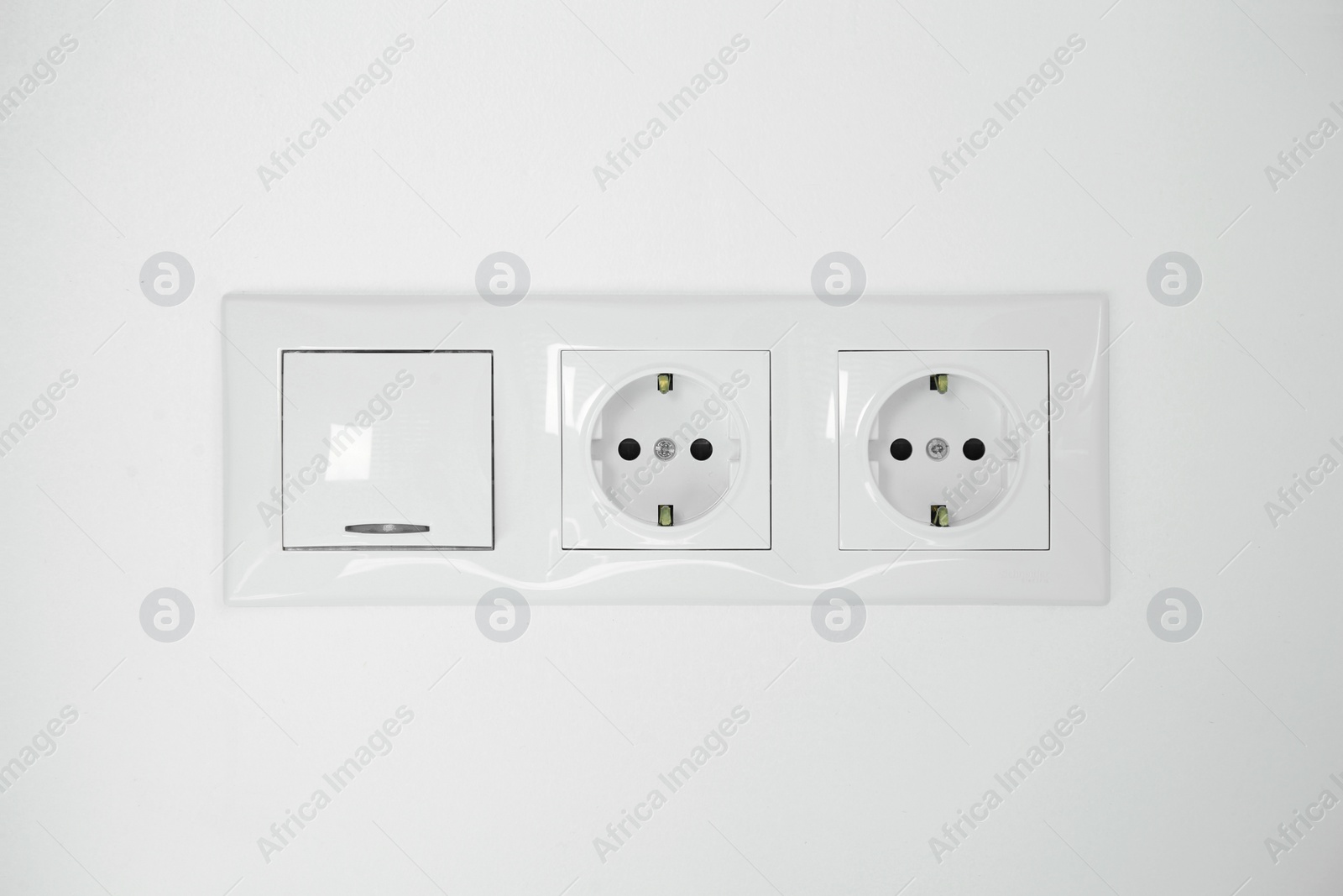 Photo of Light switch and power sockets on white wall indoors