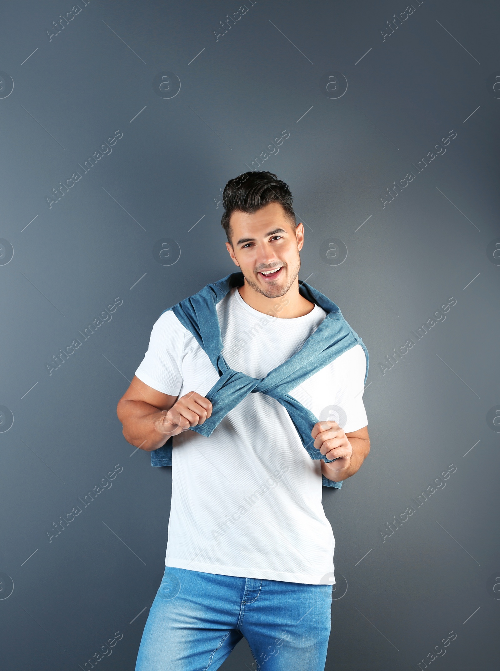 Photo of Young man in stylish jeans on grey background