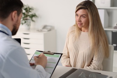 Professional doctor working with patient at white table in hospital