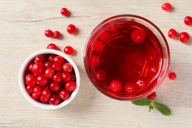 Photo of Tasty refreshing cranberry juice, mint and fresh berries on light wooden table, flat lay