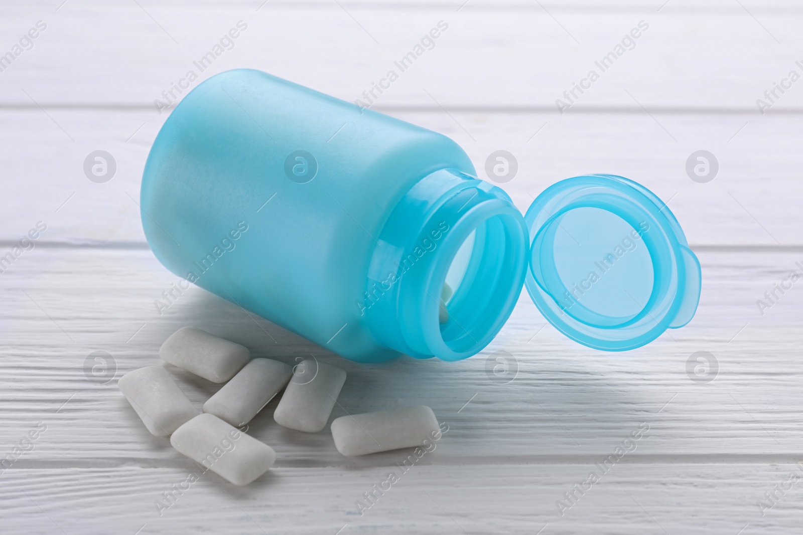 Photo of Jar with chewing gums on white wooden table