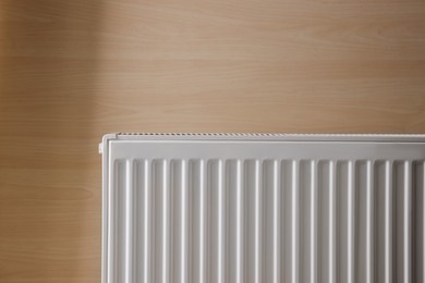 Photo of Modern radiator on wooden wall. Central heating system