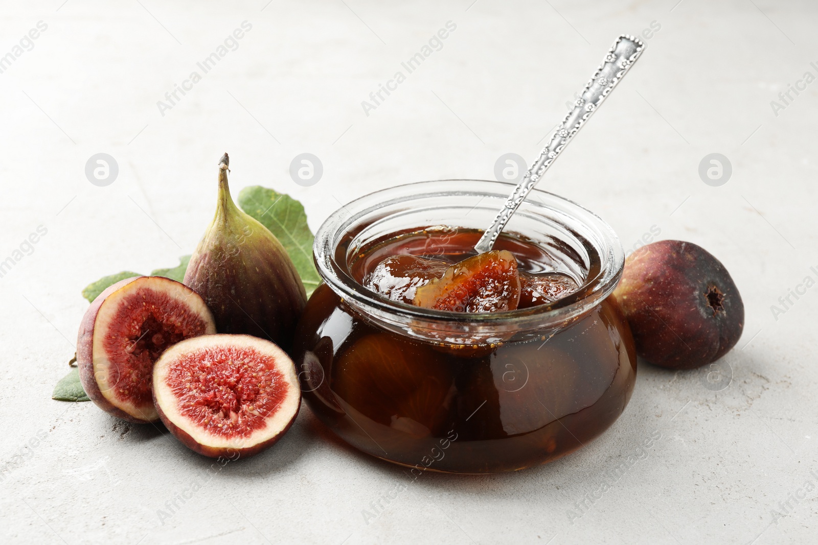 Photo of Jar of tasty sweet jam and fresh figs on white table