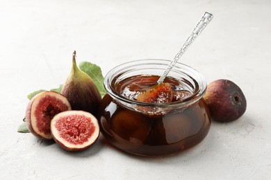 Jar of tasty sweet jam and fresh figs on white table