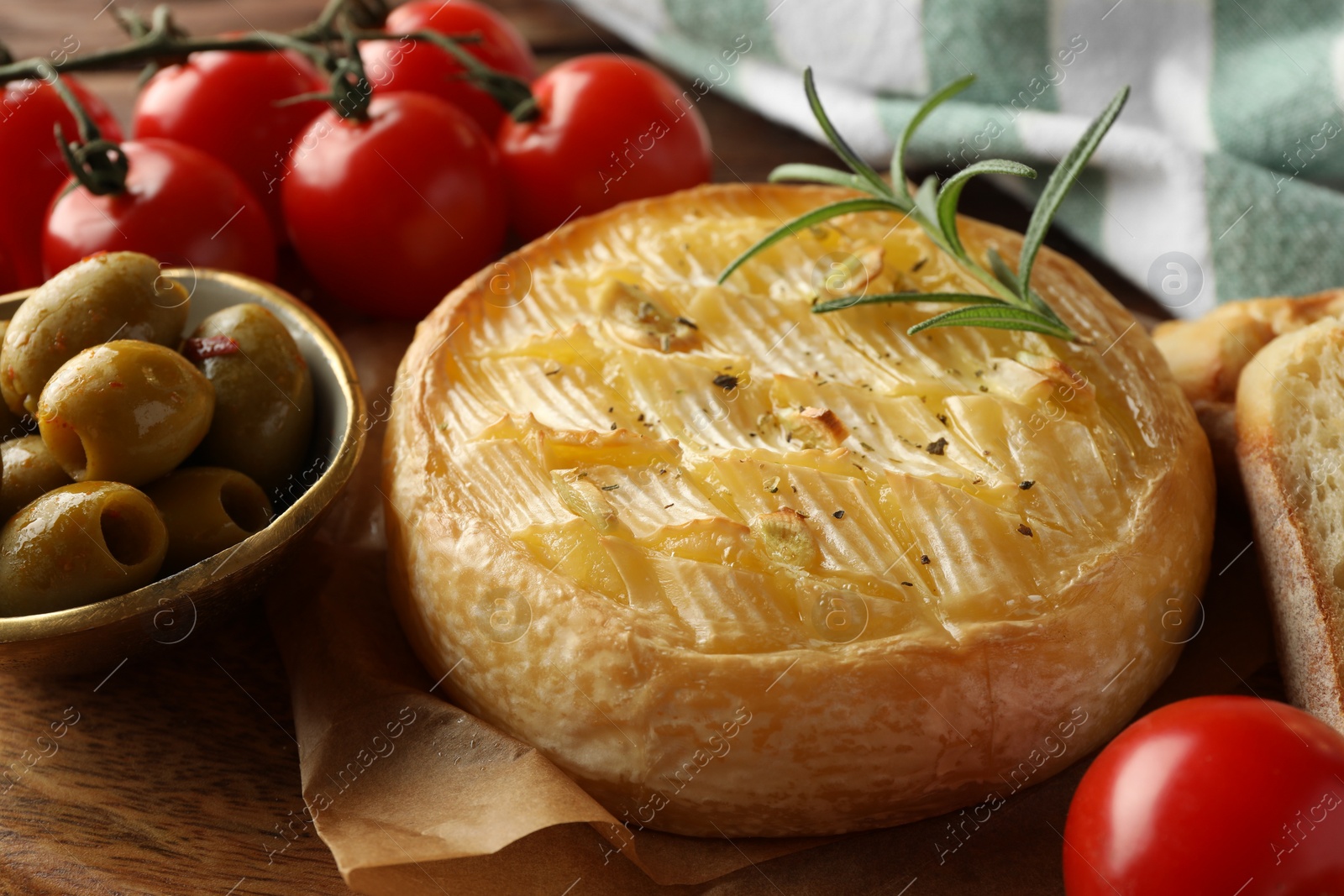 Photo of Tasty baked brie cheese served on wooden board, closeup