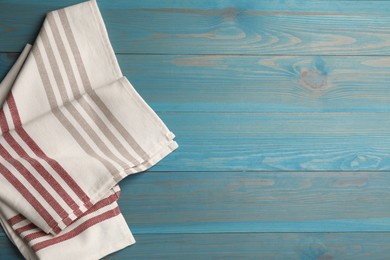 Photo of Striped kitchen towel on light blue wooden table, top view. Space for text