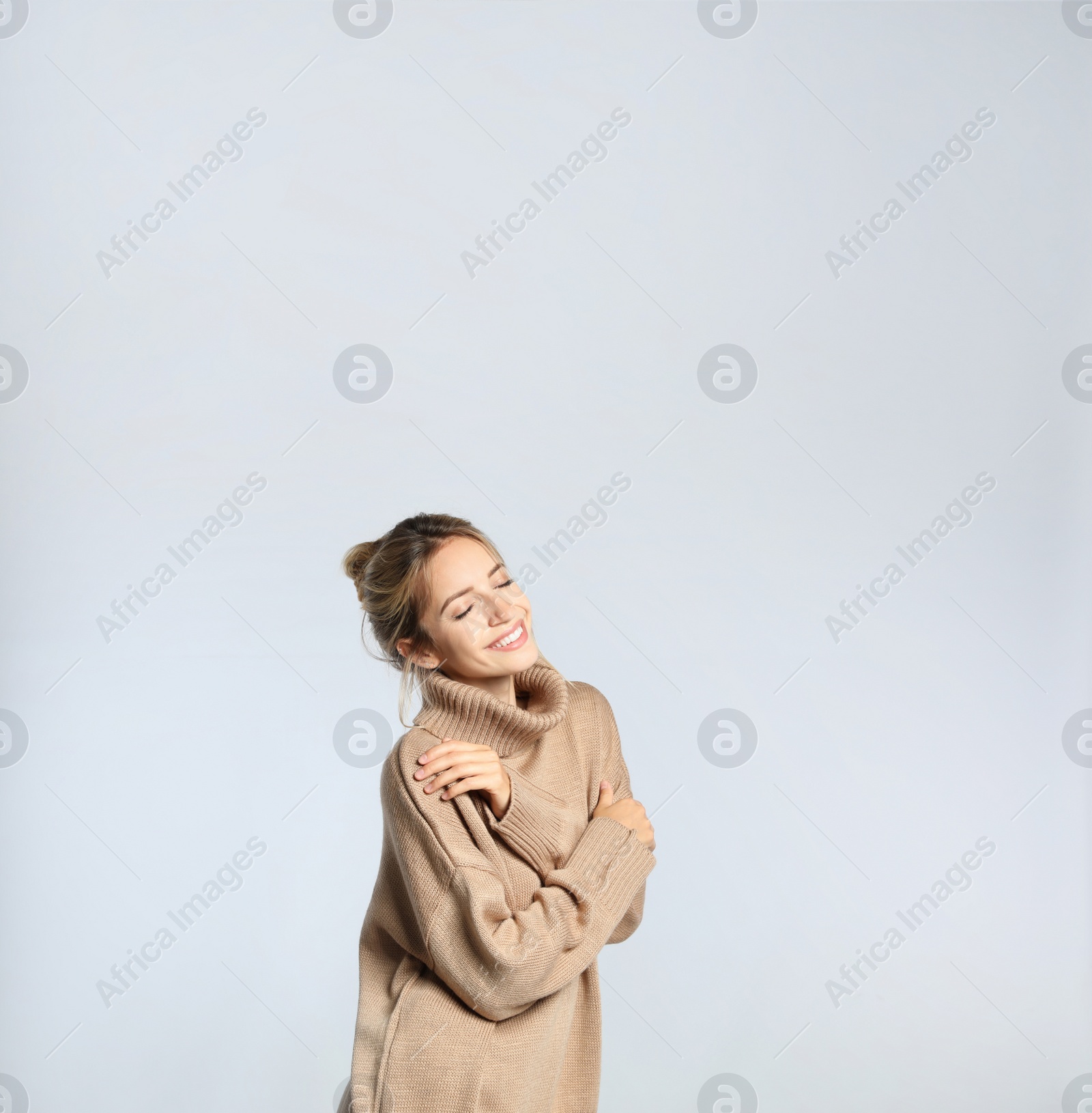 Photo of Beautiful young woman wearing knitted sweater on light grey background