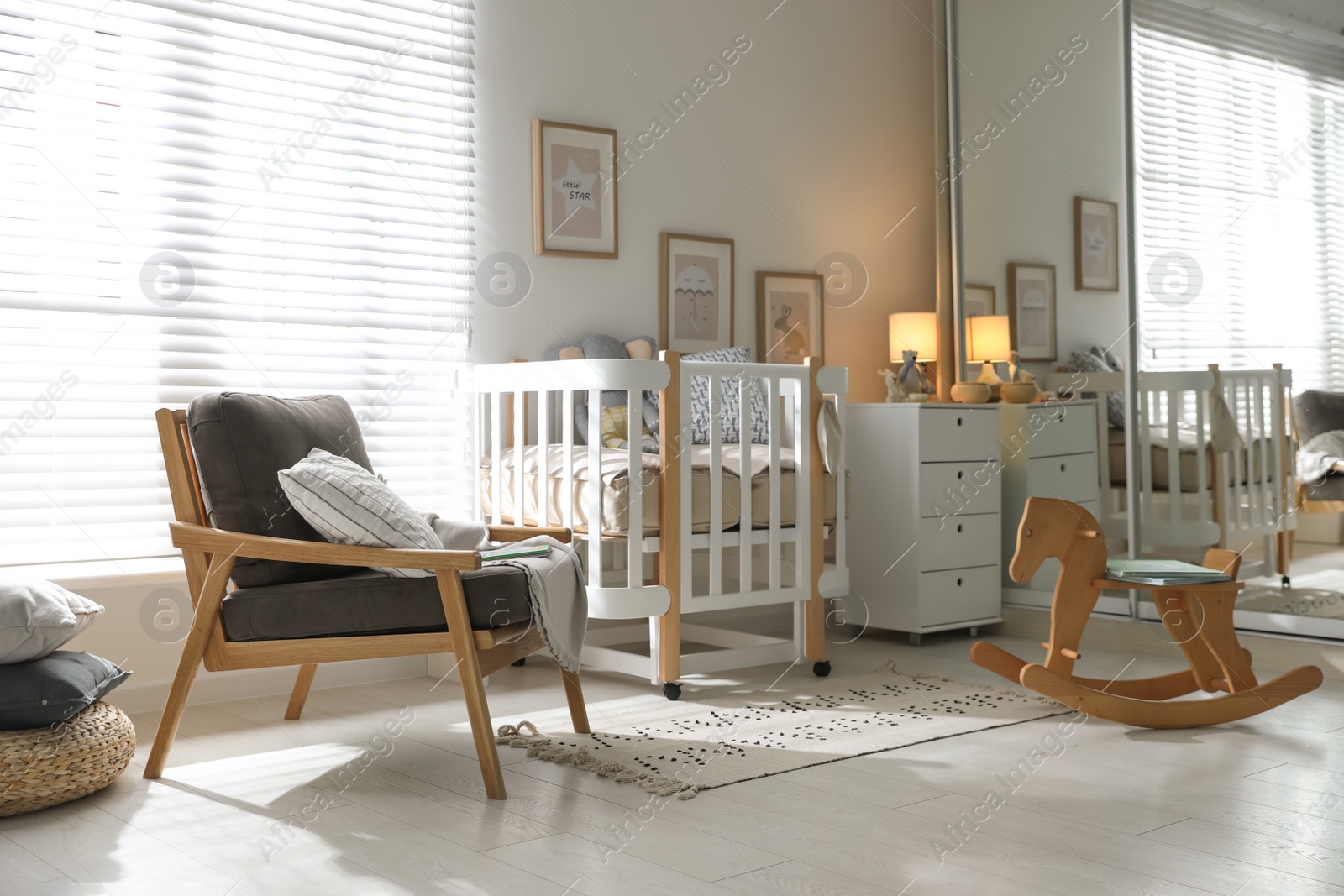 Photo of Baby room interior with crib, rocking horse and armchair