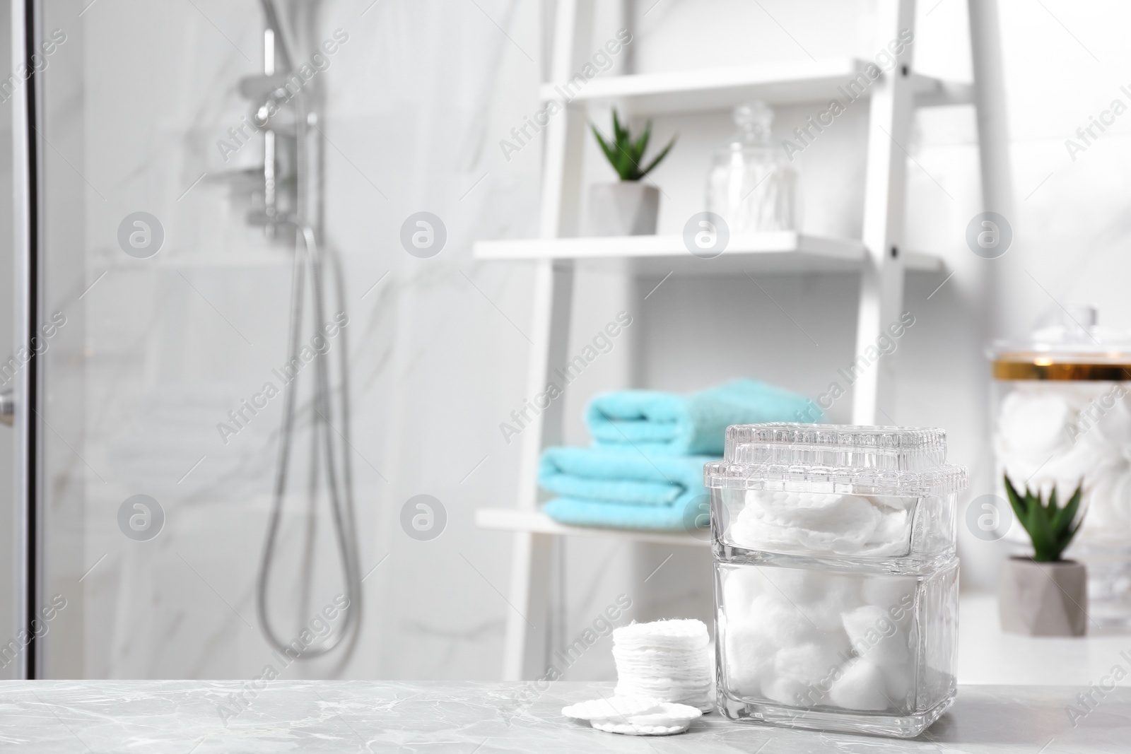 Photo of Cotton pads and balls on light grey marble table in bathroom