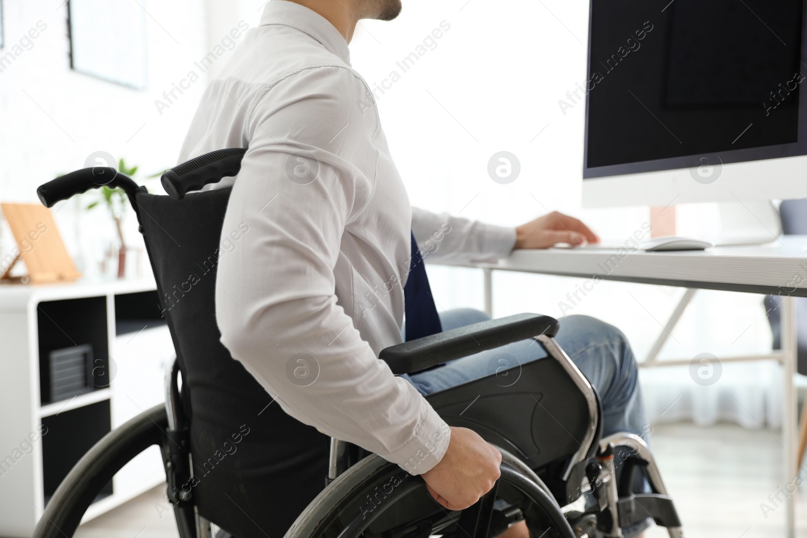 Photo of Young man in wheelchair at workplace, closeup