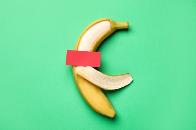 Photo of Banana with censor bar on green background, top view