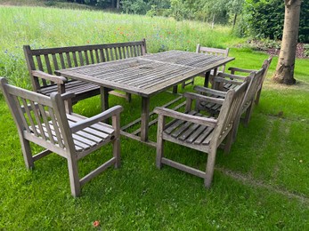 Wooden table with bench and chairs in garden. Landscape design