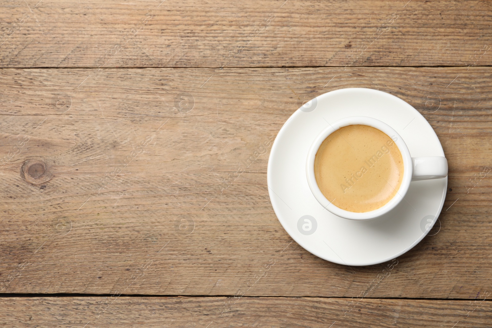 Photo of Aromatic coffee in cup on wooden table, top view. Space for text