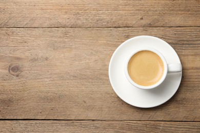 Photo of Aromatic coffee in cup on wooden table, top view. Space for text