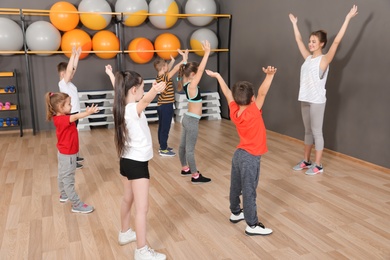 Cute little children and trainer doing physical exercise in school gym. Healthy lifestyle