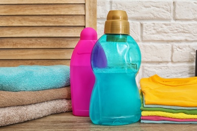 Photo of Clean clothes, towels and bottles with detergents on table