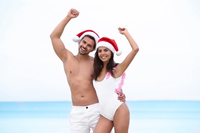 Photo of Happy young couple with Santa hats together on beach