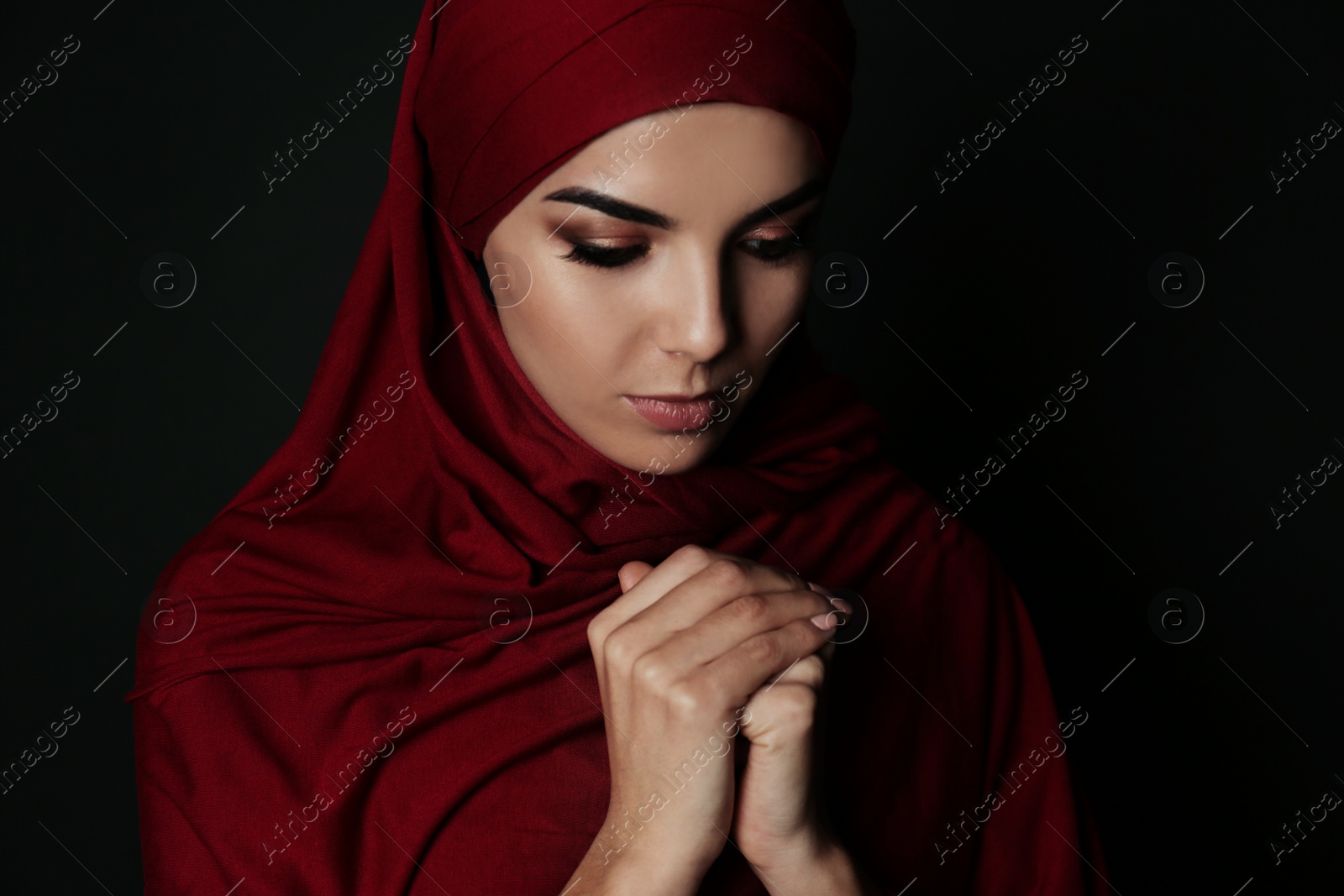 Photo of Portrait of Muslim woman in hijab  praying on dark background