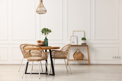 Photo of Dining room interior with wooden table and wicker chairs