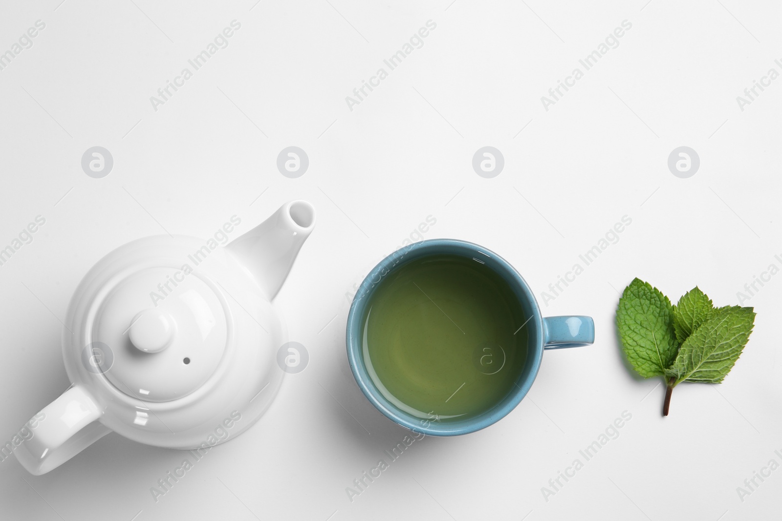 Photo of Cup with hot tea, mint and teapot on white background, top view