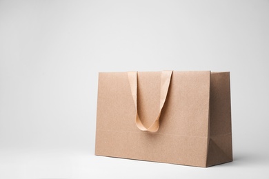 Photo of Paper shopping bag with comfortable handles on white background. Mockup for design