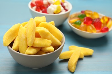 Photo of Delicious gummy fruit shaped candies on light blue wooden table, closeup